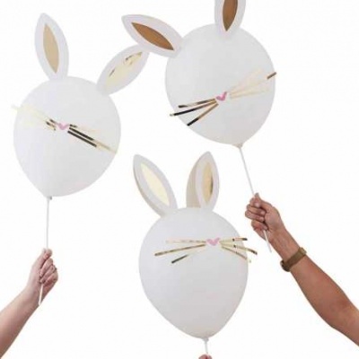 Balões brancos com desenhos de coelho sendo segurados por mãos