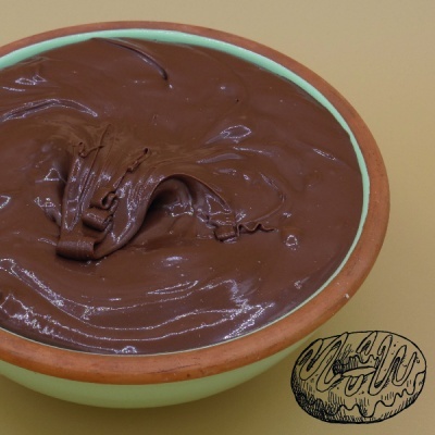 Tigela verde com creme de chocolate espesso e desenho de chocolate ao lado