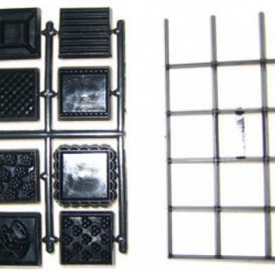 Moldes de plástico preto e grelha metálica prateada sobre fundo branco