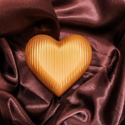 Coração de madeira com textura estriada sobre tecido de cetim castanho escuro