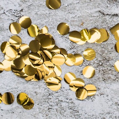 Confetes dourados redondos sobre superfície cinzenta.