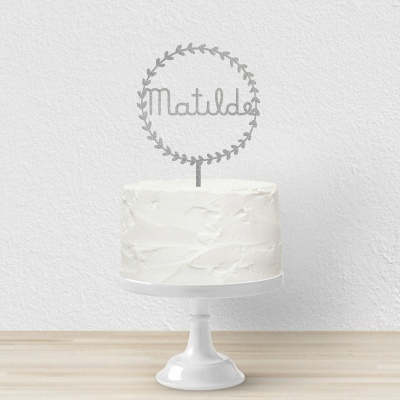 Bolo branco com cobertura texturizada e topper decorativo com o nome Matilde