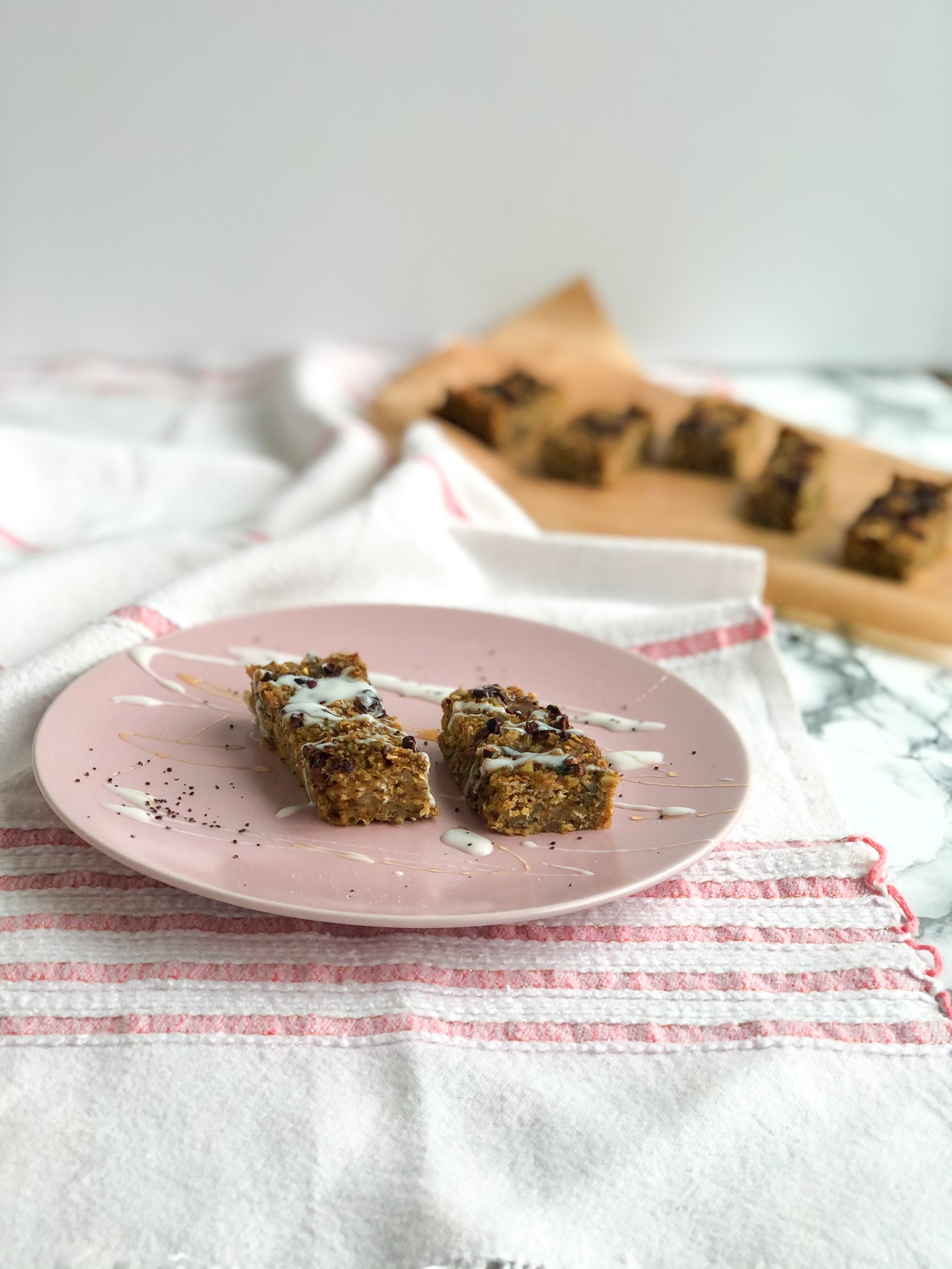 Barras integrais de aveia e chocolate no prato rosa com toalha branca e riscas vermelhas