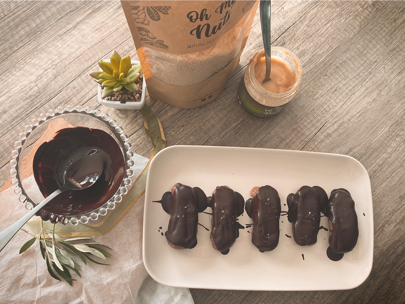 Espetadas de fruta com cobertura de chocolate e recipiente com chocolate derretido sobre mesa de madeira cinza