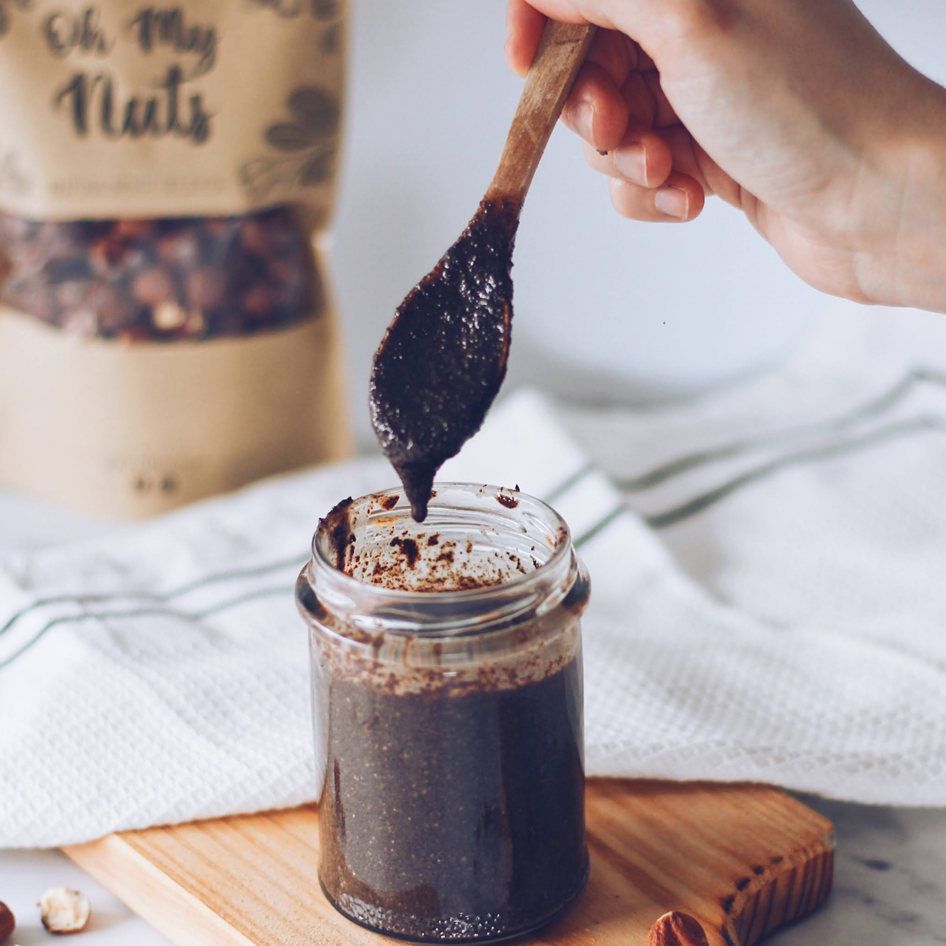 Frasco de vidro com pasta castanha escura e colher de pau a retirar pasta