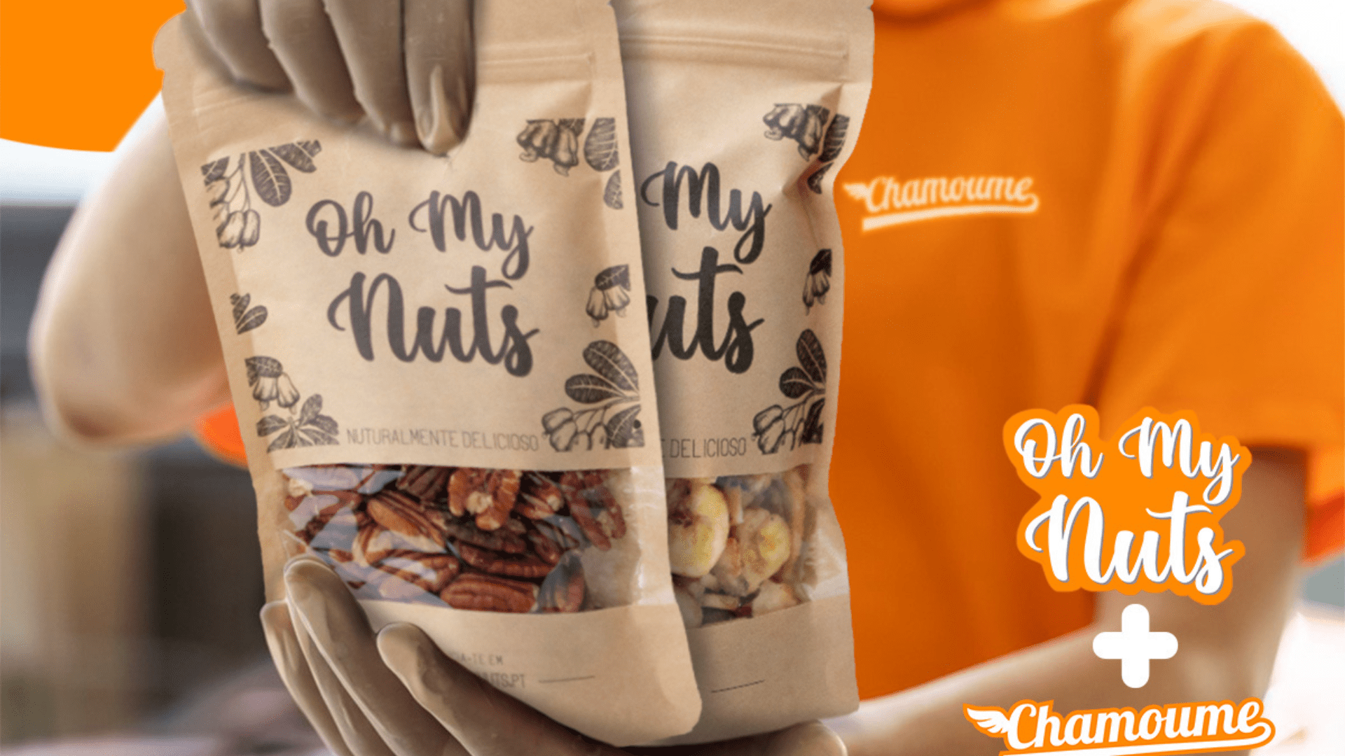 Pacotes 'Oh My Nuts' contendo nozes em embalagem de material couro natural sendo segurados por pessoa com camiseta laranja.