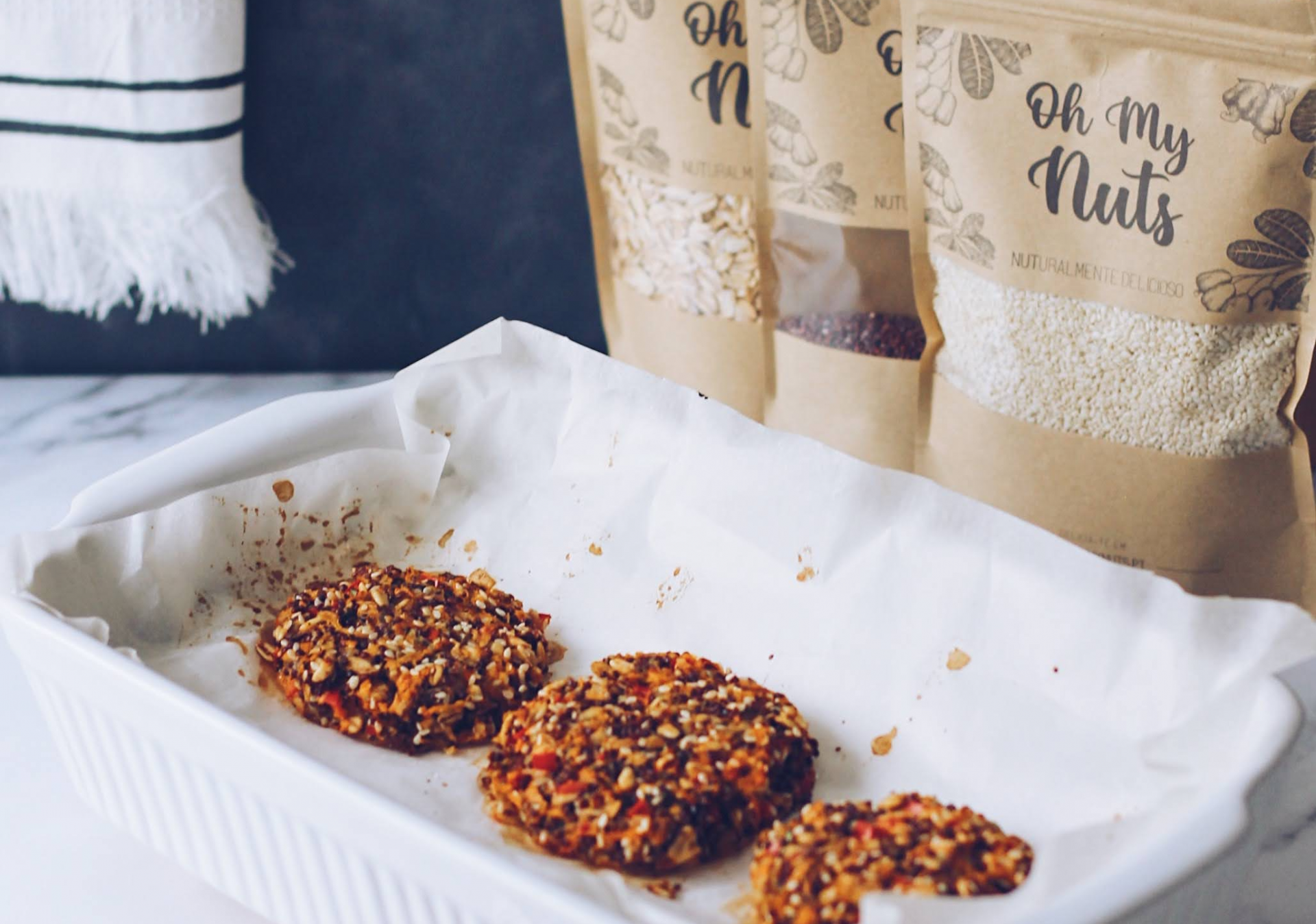 Bolachas de aveia com frutos secos numa travessa branca e embalagens 