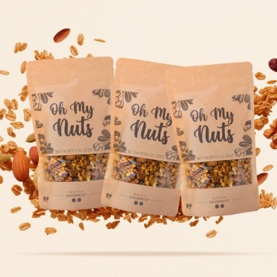 Três pacotes de granola Oh My Nuts com nozes e grãos ao redor em fundo bege.