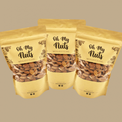 Três pacotes de amêndoas Oh My Nuts em fundo castanho