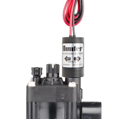 válvula solenoide Hunter preta com fios vermelhos e pretos, etiqueta metálica com texto e fundo branco