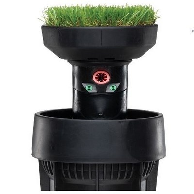 Dispositivo preto com plantação artificial verde no topo e detalhes vermelhos e verdes na parte frontal
