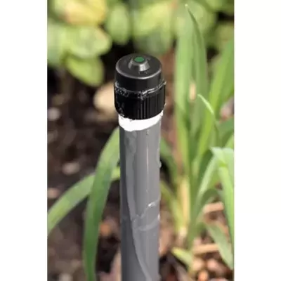 Aspersor preto e cinza num jardim com plantas