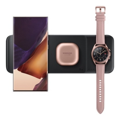 Telefone Samsung, auriculares e relógio inteligente cor de rosa sobre base de carregamento preta