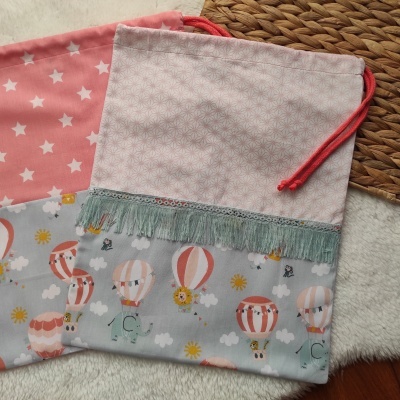 Sacos de tecido com padrões coloridos e franjas, sobre superfície macia e tapete de fibra