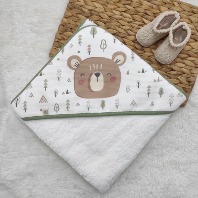 Toalha de bebé branca com capuz com padrão de ursinho e árvores, e botinhas de bebé