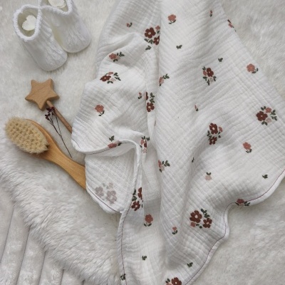 Manta branca com flores vermelhas e verdes, escova de madeira, chupeta de estrela e botinhas brancas.