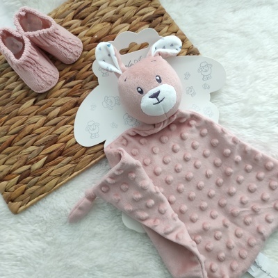 Vestido rosa com cabeça de coelho e sapatinhos rosas sobre tapete de fibras naturais