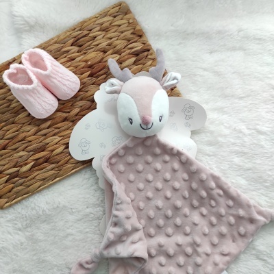 Manta cor-de-rosa claro com cabeça de cervo e botinhas cor-de-rosa sobre tapete de palha