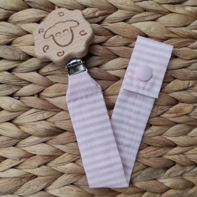 Prendedor de chupeta em madeira e tecido rosa com riscas sobre palha