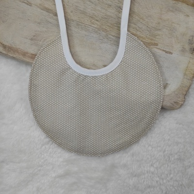 Babete redondo bege com padrão de pontos brancos e borda branca