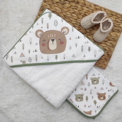 Toalha de banho para bebé com padrão de ursinhos e sapatinhos sobre tapete natural