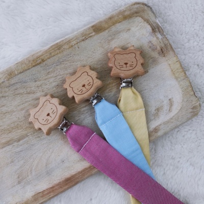 Três presilhas de chupeta com fechos de madeira em forma de leão e fitas coloridas em tecido