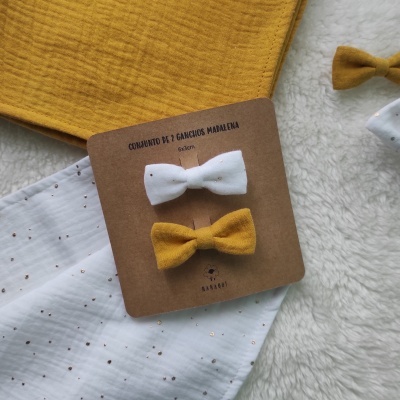 Conjunto de 2 ganchos para cabelo em tecido branco e amarelo mostarda sobre tecidos e cartão.