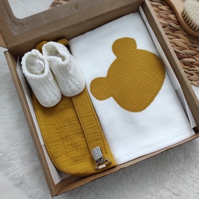 Caixa com manta branca e amarelo com padrão de urso, faixa amarela e sapatinhos brancos de malha