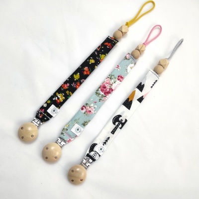 Três fitas para chupeta com clipes de madeira e estampas coloridas distintas