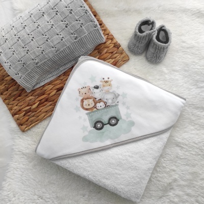 Toalha de banho de bebé com bordado de animais, mantinha cinza e sapatinhos cinzentos sobre fundo claro felpudo