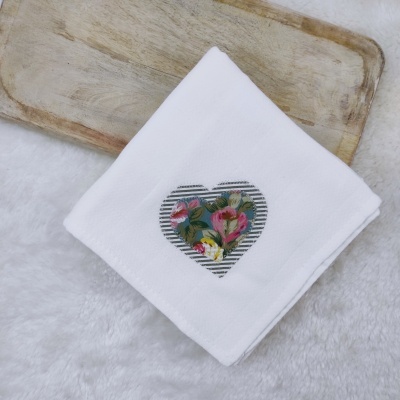 Guardanapo branco com coração estampado floral sobre madeira