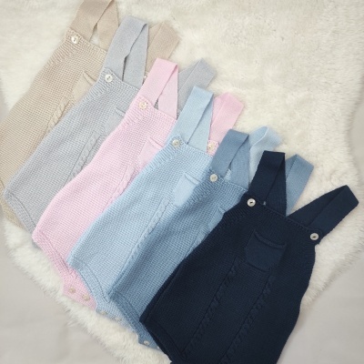 Macacões de malha para bebé em várias cores dispostos em tapete branco