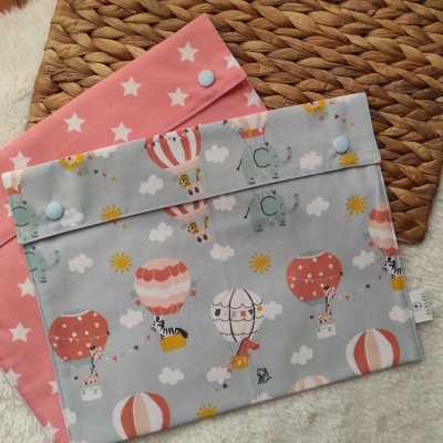 Dois sacos de tecido infantis com estampados de balões de ar quente e estrelas, com fecho azul claro.