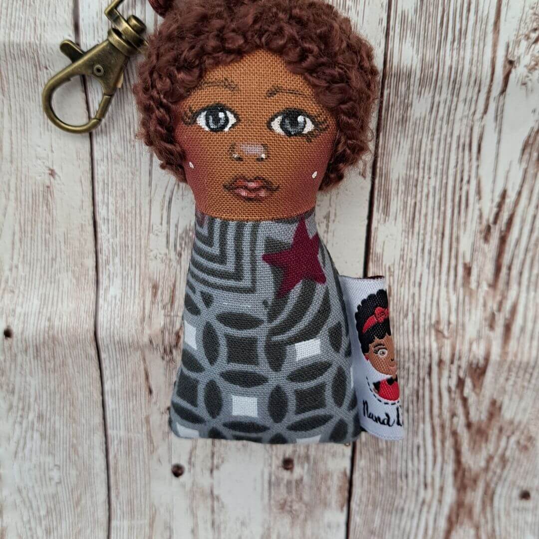 Porta-Chaves Boneca – Delicadeza e Força Chaveiro de tecido com rosto bordado e mosquetão dourado