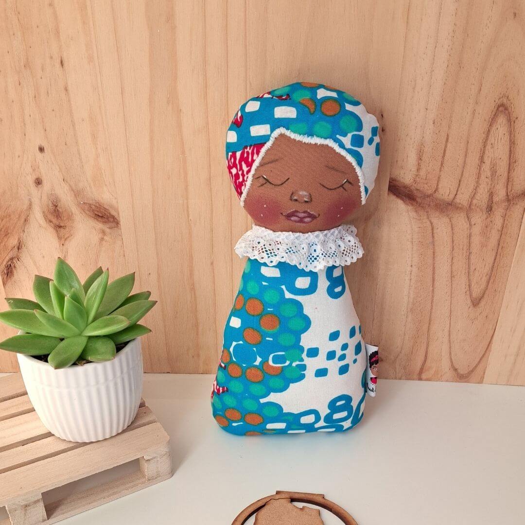 Naninha Boneca de pano colorida junto a planta suculenta e fundo de madeira