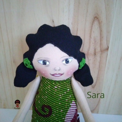 Boneca de pano com cabelo preto e vestido verde com padrões