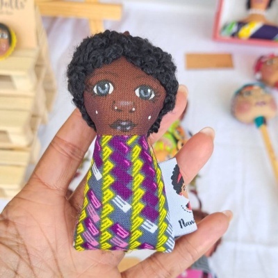 Boneco artesanal de tecido com vestido colorido e cabelo encaracolado