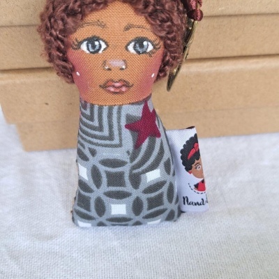 Boneco tecido com rosto pintado e roupa cinza com padrão