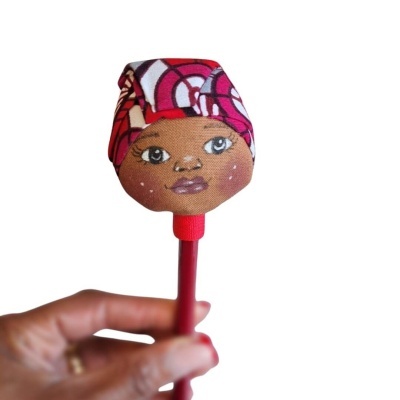 Caneta vermelha com tampa decorada com cabeça de tecido e rosto pintado