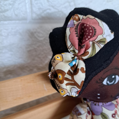 Boneca de tecido com cabelo preto e acessórios florais coloridos no cabelo