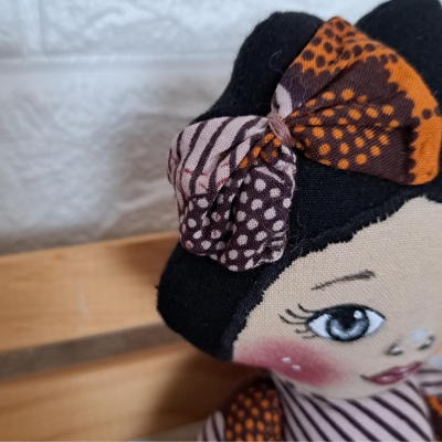 Boneca de tecido com cabelo preto e laço colorido