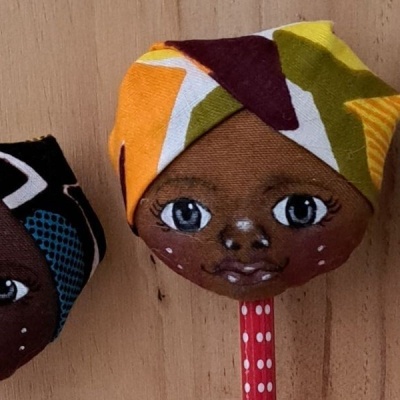 Três bonecas de tecido com lenços coloridos e olhos pintados