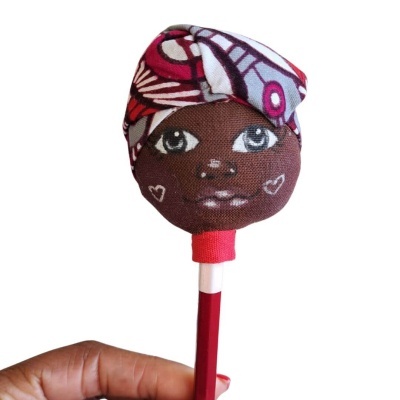 Boneca de tecido com rosto pintado à mão e lenço colorido montada numa haste vermelha