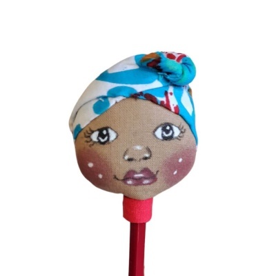 Boneca de tecido com rosto pintado e cachecol azul numa ponta de lápis vermelho