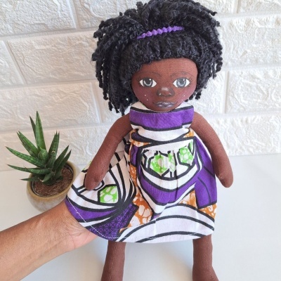 Boneca de pano com vestido colorido e cabelo preto encaracolado