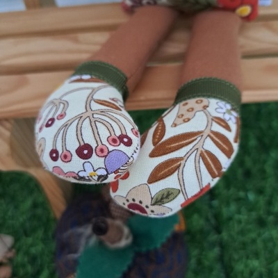 Pés de boneca com meias estampadas florais e folhagem em tons castanhos, verdes, vermelhos e roxos