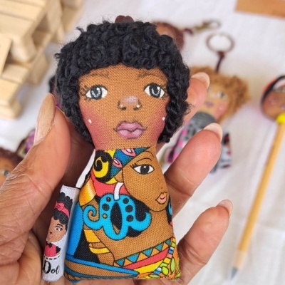 Boneco de pano artesanal colorido com cabelo preto encaracolado