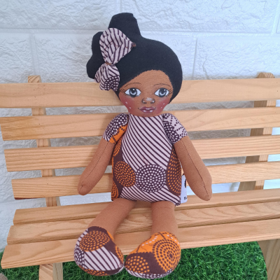 Boneca de pano vestida com padrão colorido sentada num banco de madeira