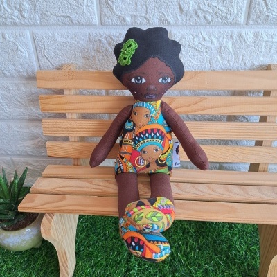 Boneca de tecido colorida sentada num banco de madeira