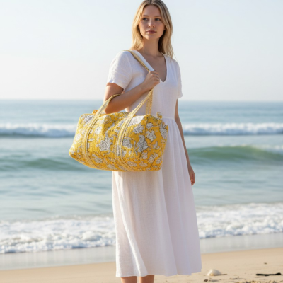 Mulher na praia com vestido branco e bolsa amarelo floral